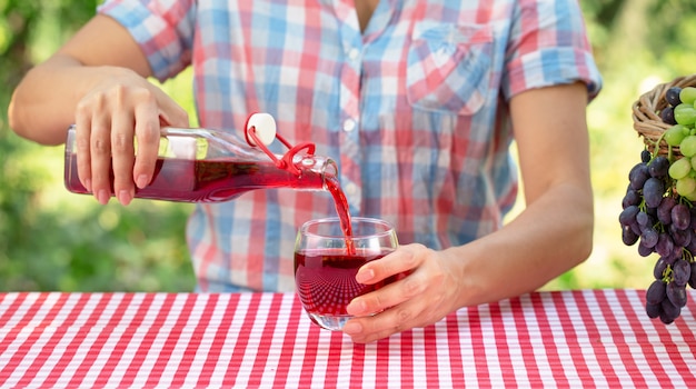 Femme verse du jus de raisin ou du vin dans un verre