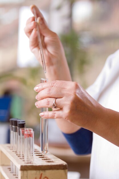 Femme verse une goutte de liquide dans un flacon en verre