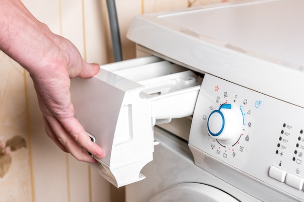 Femme verser le détergent en poudre à laver dans la machine à laver