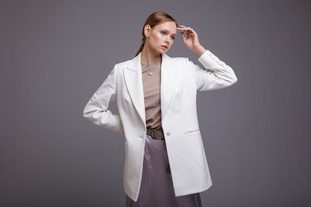 Femme en veste blanche longue jupe argentée métallique posant sur fond gris Studio Shot Portrait