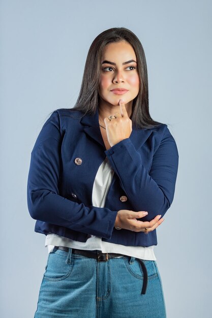 Une femme en veste bleue se tient devant un fond gris.