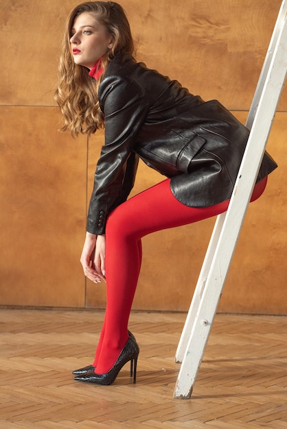 Photo femme avec une veste en cuir noire et un pantalon rouge