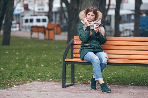 femme avec veste dans le parc est assis sur un banc