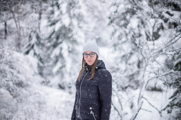 Femme en veste d'hiver marchant dans la forêt d'hiver enneigée journée d'hiver enneigée