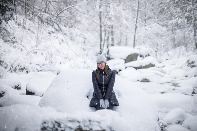 Femme en veste d'hiver marchant dans la forêt d'hiver enneigée journée d'hiver enneigée