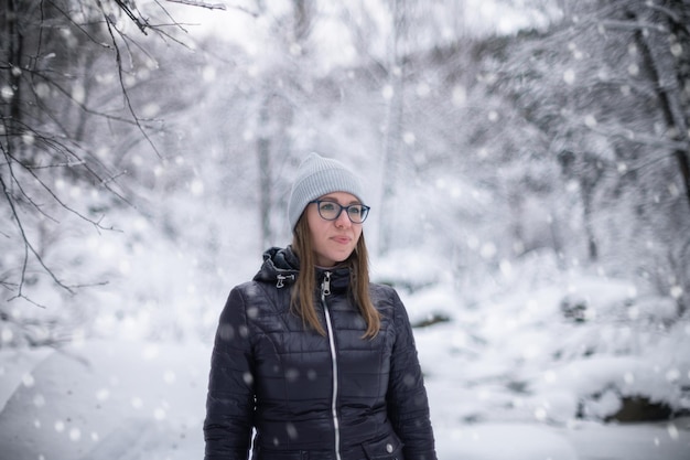 Femme en veste d'hiver marchant dans la forêt d'hiver enneigée journée d'hiver enneigée