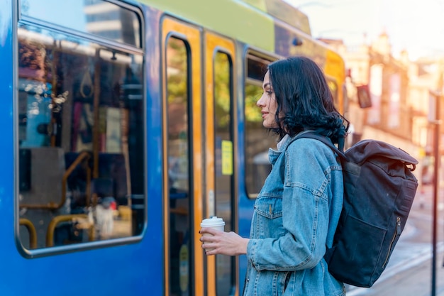 femme en veste en jean parle au téléphone et attend un tram à l'arrêt photo de style de vie