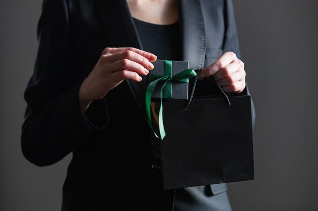 Femme en veste noire tenir la boîte-cadeau