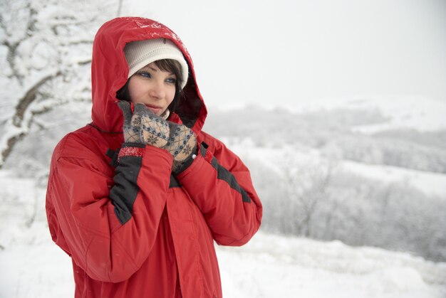 femme avec veste rouge et gants dans la forêt de neige
