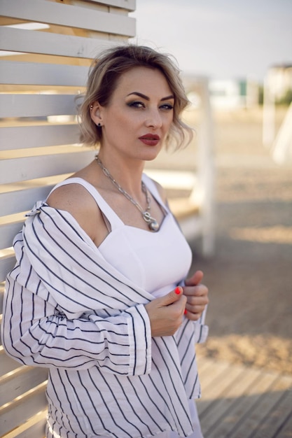 Une femme en vêtements blancs se tient sur la plage près de maisons en bois un lit de soleil intérieur