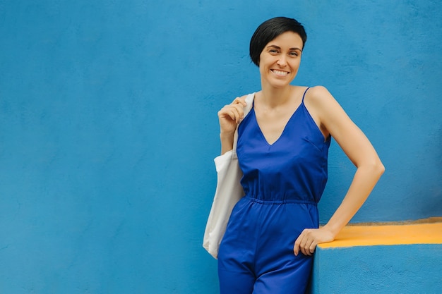 Femme en vêtements bleus sur fond bleu clair dans la ville.