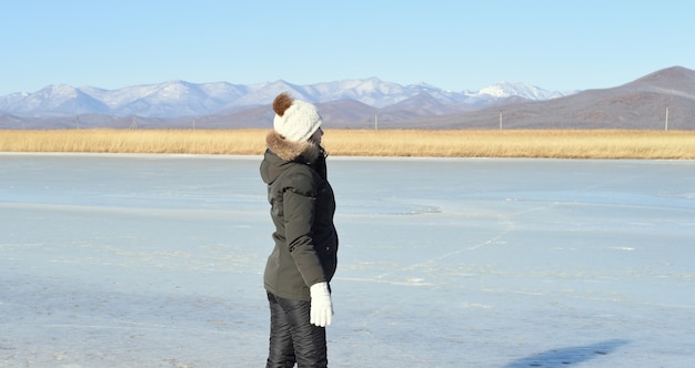 Femme en vêtements chauds debout sur la glace et à l'écart