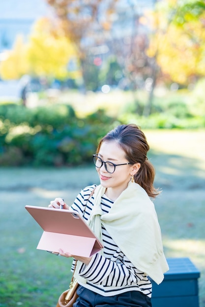 Femme en vêtements décontractés à l'aide d'une tablette PC à l'extérieur