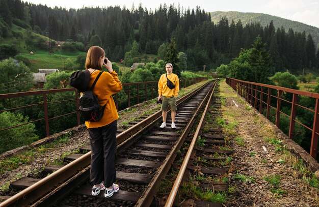 Une femme en vêtements décontractés fait une photo devant un appareil photo pour un beau jeune randonneur dans les montagnes