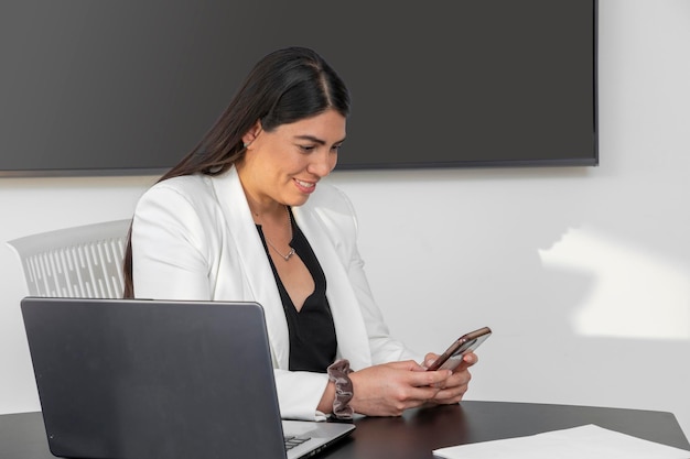 Femme en vêtements formels souriant tout en envoyant des SMS sur son téléphone portable