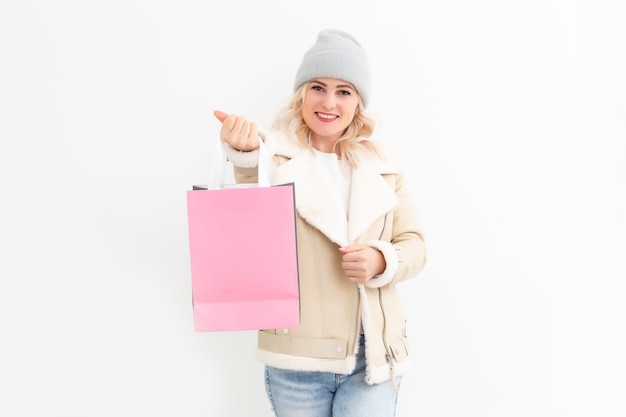 Femme en vêtements d'hiver avec des cadeaux, des cadeaux et des sacs à provisions souriant