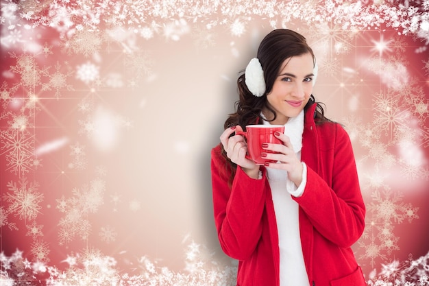 Femme en vêtements d'hiver tenant une tasse contre la conception de flocon de neige blanc sur rouge