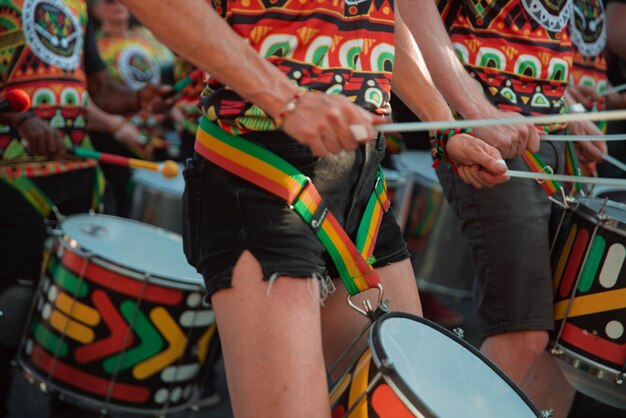 Femme en vêtements à motifs brillants et en shorts noirs jouant de tambours en acier lors d'un festival de rue