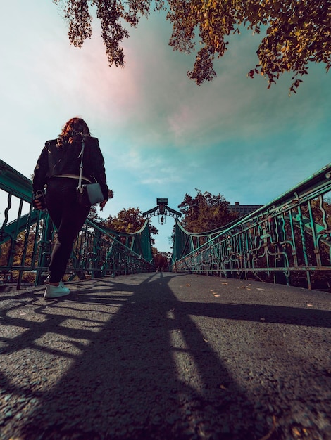 Femme en vêtements noirs traversant le pont de la ville