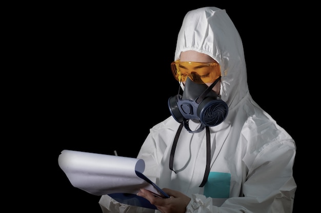 Femme en vêtements de protection chimique et masque antigaz avec des lunettes à fond blanc, femmes scientifiques en combinaison de sécurité, concept d'infection par le virus de la sécurité