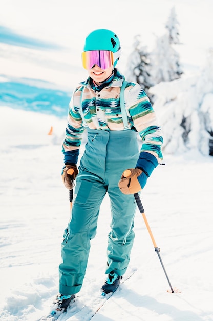 Femme en vêtements de ski avec casque et lunettes de ski sur la tête avec des bâtons de ski Météo hivernale sur les pistes Au sommet d'une montagne et profitant de la vue Ski alpin Sport d'hiver