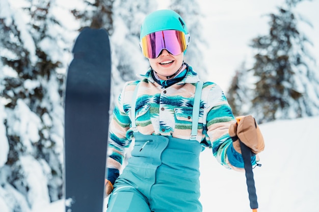 Femme en vêtements de ski avec casque et lunettes de ski sur la tête avec des bâtons de ski Météo hivernale sur les pistes Au sommet d'une montagne et profitant de la vue Ski alpin Sport d'hiver