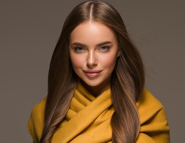 Femme en vêtements tricotés cheveux longs de style automne hiver jaune. Fond de couleur marron