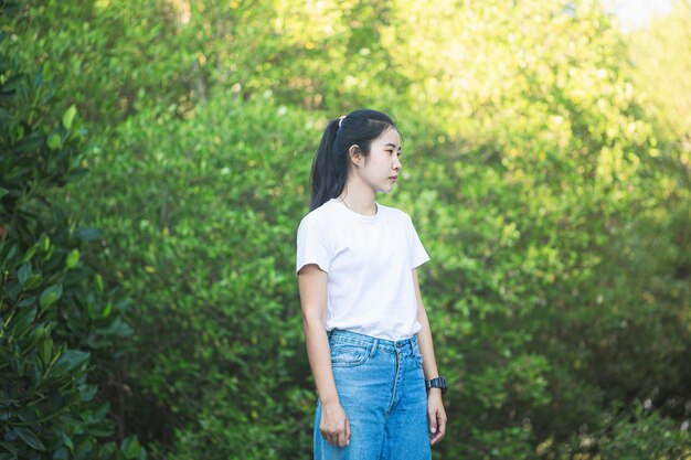 Une femme vêtue de blanc a un fond de feuille verte Jolie fille asiatique assise