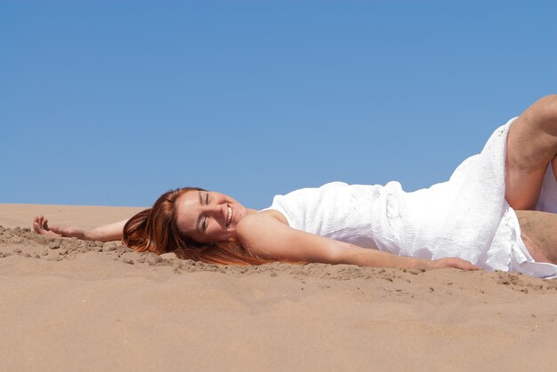 femme vêtue de blanc profitant des dunes de sable par une journée ensoleillée de printemps ou d'été