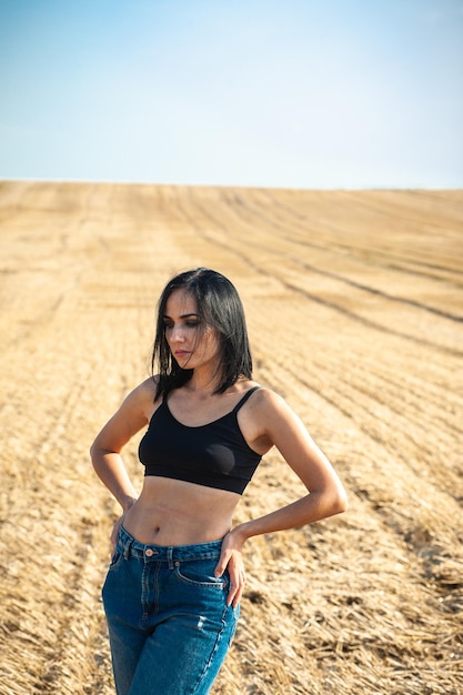 Une femme vêtue d'un haut noir et d'un jean se tient dans un champ.