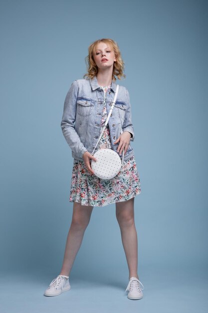 Photo femme vêtue d'une jolie robe colorée avec une veste en jean à motif floral