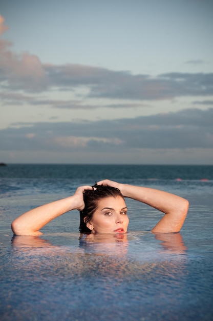 Femme vêtue prenant un bain au coucher du soleil