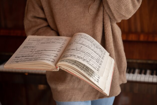 Une femme vêtue d'un pull douillet tient une collection de notes de musique.