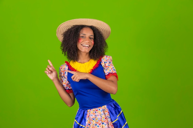 Une femme vêtue d'une robe bleue et d'un chapeau de paille pointe du doigt quelque chose.