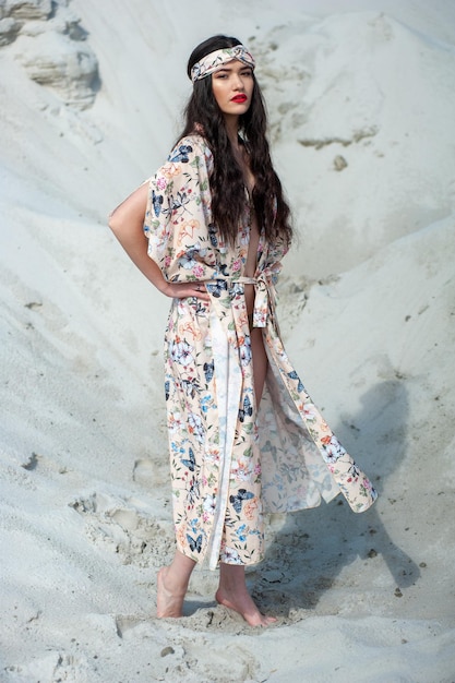 Une femme vêtue d'une robe à fleurs se tient sur une plage.