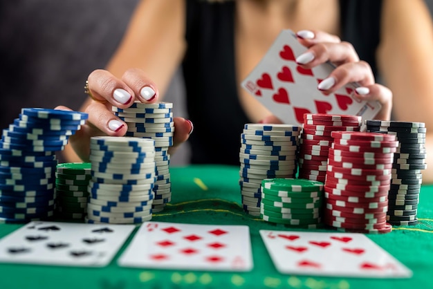 Une femme vêtue d'une robe noire du soir joue au poker dans un casino enveloppant tous les gains dans ses mains