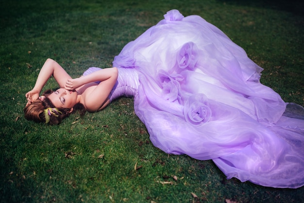 Photo femme vêtue d'une robe rose marchant dans un jardin fleuri