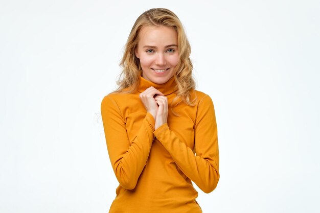 Femme vêtue de vêtements jaunes regardant la caméra avec un sourire charmant timide