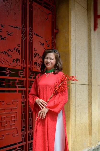 Une femme vietnamienne en robe rouge ao dai pour les fêtes du Tet