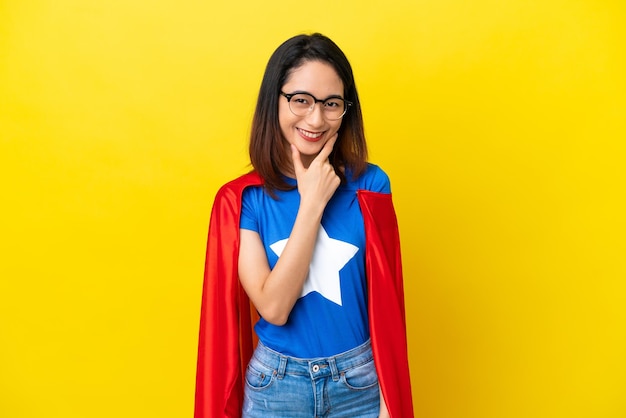 Femme vietnamienne de super héros isolée sur fond jaune avec des lunettes et souriant