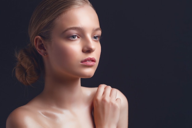 femme avec un visage clair et une peau propre sur un mur noir