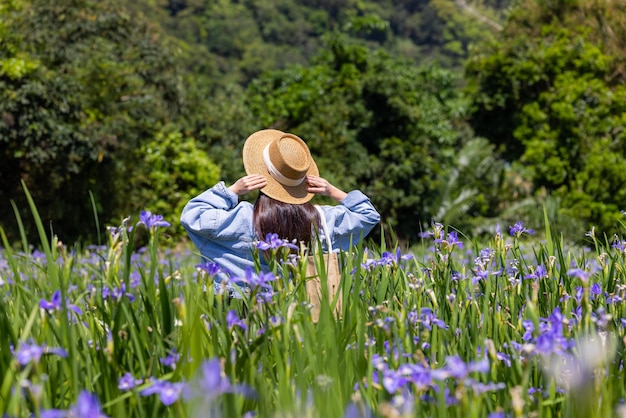 Une femme visite le champ de fleurs avec une fleur d'iris tectorum