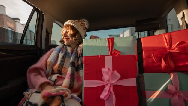 Femme en voiture avec des cadeaux de Noël