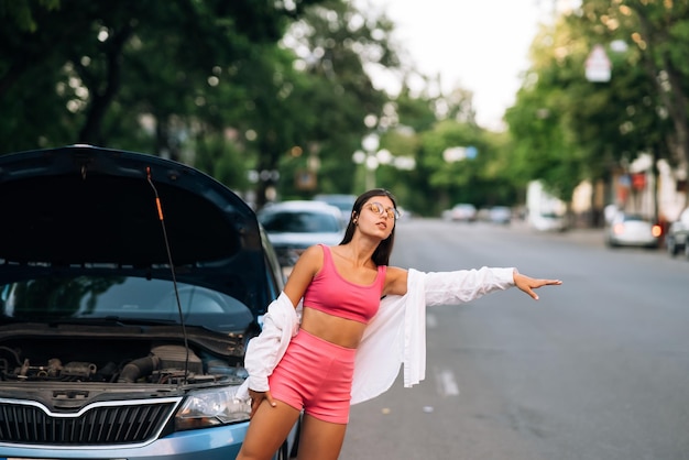 Femme avec une voiture cassée sur la route Cherchez de l'aide