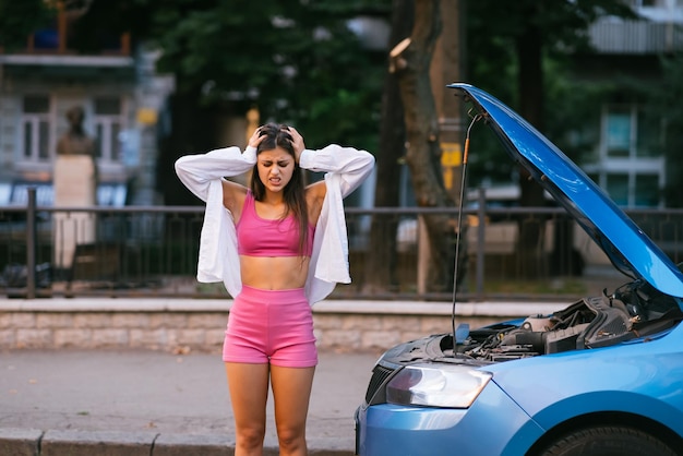 Femme avec une voiture cassée sur la route Cherchez de l'aide