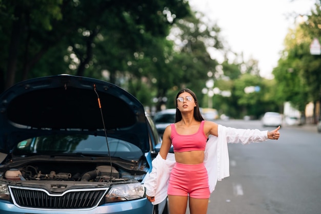 Femme avec une voiture cassée sur la route Cherchez de l'aide