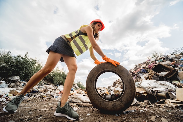 Une femme volontaire aide à nettoyer le champ des déchets plastiques et des vieux pneus. Jour de la Terre et écologie.