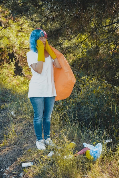 Femme volontaire au visage choqué nettoyant l'environnement de la pollution plastique