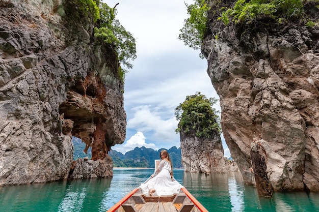 Femme de voyage assise sur un bateau près de trois célèbres rochers dans le parc de khao sok en thaïlande