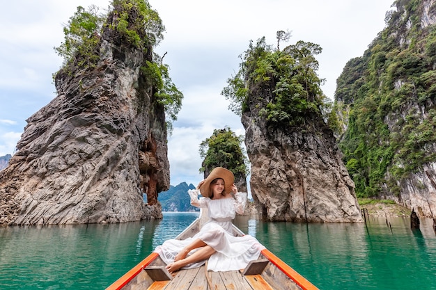 Femme de voyage assise sur un bateau près de trois célèbres rochers dans le parc de khao sok en thaïlande